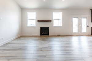 Unfurnished living room with light wood-type flooring and a healthy amount of sunlight