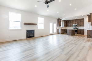 Kitchen featuring ceiling fan, a center island, stainless steel appliances, a kitchen breakfast bar, and light wood-type flooring