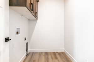 Laundry room with light hardwood / wood-style floors, washer hookup, cabinets, and hookup for an electric dryer