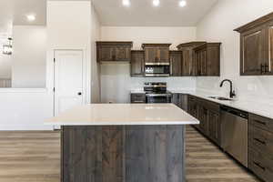 Kitchen featuring light stone countertops, appliances with stainless steel finishes, a kitchen island, and sink