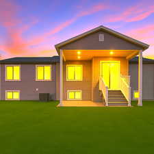 Back of property at dusk featuring a lawn