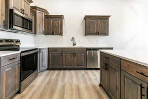 Kitchen with light hardwood / wood-style floors, sink, dark brown cabinetry, and stainless steel appliances