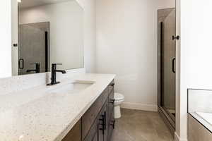 Bathroom with tile patterned flooring, vanity, a shower with shower door, and toilet