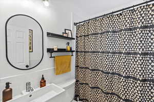 Bathroom with decorative backsplash, a shower with curtain, toilet, and sink