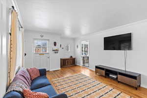 Living room with wood-type flooring and ornamental molding