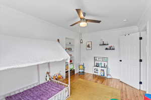 Bedroom with ceiling fan, crown molding, and hardwood / wood-style flooring