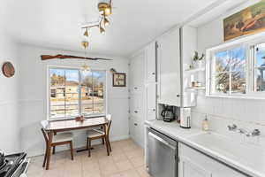 Kitchen featuring sink, a wealth of natural light, appliances with stainless steel finishes, decorative light fixtures, and white cabinetry