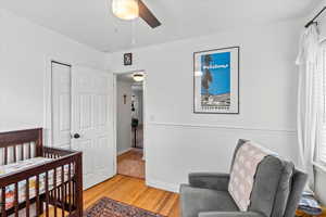 Bedroom featuring ceiling fan, light hardwood / wood-style floors, a crib, and a closet