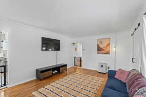 Living room featuring a barn door, hardwood / wood-style flooring, and crown molding