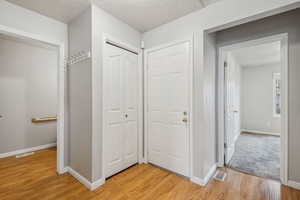 Hall with a textured ceiling and light wood-type flooring