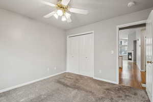 Unfurnished bedroom with carpet flooring, ceiling fan, a fireplace, and a closet