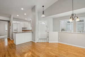 Kitchen with white cabinets, decorative light fixtures, kitchen peninsula, and a chandelier