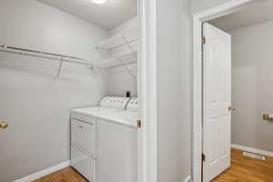 Clothes washing area featuring washer and clothes dryer, light hardwood / wood-style floors, and a textured ceiling