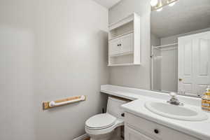 Bathroom featuring walk in shower, vanity, and toilet