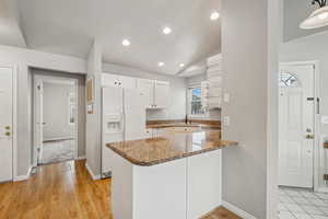 Kitchen featuring white cabinetry, sink, kitchen peninsula, vaulted ceiling, and white appliances