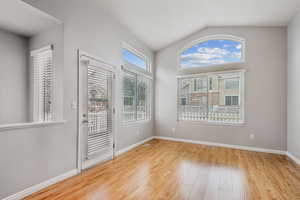 Empty room with hardwood / wood-style flooring and lofted ceiling