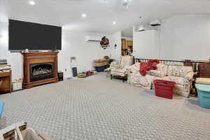 Carpeted living room featuring a wall mounted air conditioner and vaulted ceiling