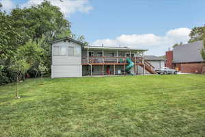 Rear view of house featuring a lawn and a deck