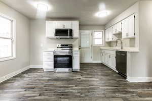 Kitchen featuring sink, dark hardwood / wood-style flooring, white cabinetry, and appliances with stainless steel finishes