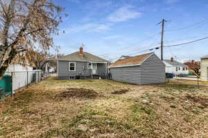 Back of house featuring a lawn and an outbuilding