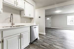 Kitchen featuring sink, stainless steel dishwasher, dark hardwood / wood-style flooring, and white cabinetry