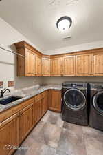 Laundry room featuring washing machine and dryer, sink, and cabinets