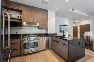 Kitchen featuring light hardwood / wood-style floors, stainless steel appliances, kitchen peninsula, sink, and extractor fan