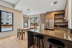 Kitchen featuring light hardwood / wood-style floors, kitchen peninsula, a breakfast bar, pendant lighting, and high quality fridge