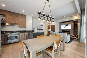 Dining room with sink, a fireplace, built in shelves, and light hardwood / wood-style flooring