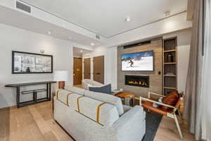 Living room featuring a tile fireplace, light hardwood / wood-style flooring, and built in features