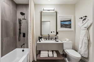 Full bathroom with shower / bathtub combination with curtain, sink, and toilet