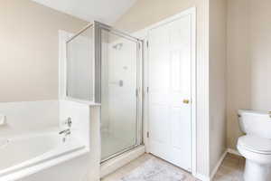 Bathroom featuring plus walk in shower, lofted ceiling, and toilet