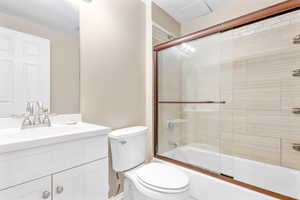 Full bathroom with shower / bath combination with glass door, vanity, and toilet