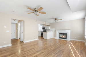 Unfurnished living room with a fireplace, ceiling fan, and wood-type flooring