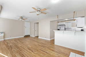 Unfurnished living room featuring ceiling fan, light hardwood / wood-style flooring, and a textured ceiling