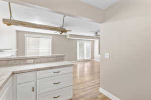 Kitchen featuring white cabinets, light hardwood / wood-style floors, and a healthy amount of sunlight