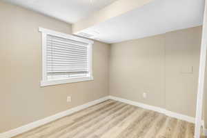 Spare room with a textured ceiling and light hardwood / wood-style flooring