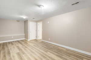 Unfurnished room with a textured ceiling and light wood-type flooring