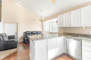 Kitchen featuring kitchen peninsula, dishwasher, a notable chandelier, hardwood / wood-style floors, and white cabinets