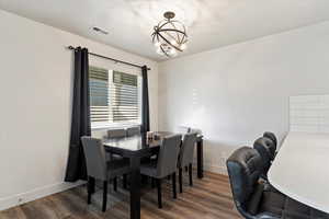 Dining area with a notable chandelier and dark hardwood / wood-style floors. Natural light throughout