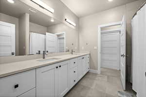 Full bathroom with double vanity, visible vents, baseboards, and a sink