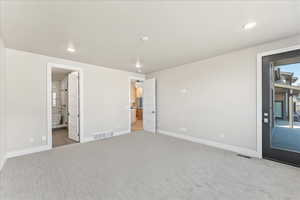 Unfurnished bedroom featuring ensuite bathroom and light carpet