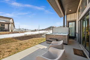 Snow covered patio with a mountain view and a hot tub