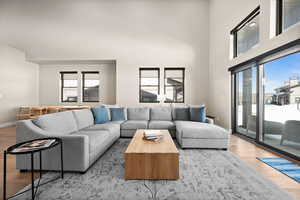 Living area featuring light wood-type flooring, baseboards, and a high ceiling