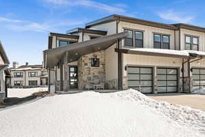 View of front of property with stone siding, driveway, an attached garage, and board and batten siding