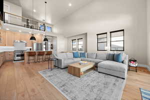 Living area featuring light wood finished floors, recessed lighting, a high ceiling, and baseboards