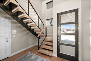 Foyer featuring a towering ceiling, baseboards, wood finished floors, and stairs