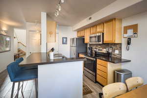 Kitchen featuring backsplash, kitchen peninsula, sink, and appliances with stainless steel finishes