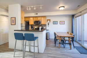 Kitchen with backsplash, kitchen peninsula, a breakfast bar, and appliances with stainless steel finishes