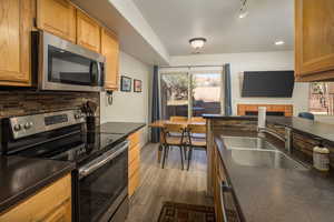 Kitchen with appliances with stainless steel finishes, backsplash, track lighting, and sink